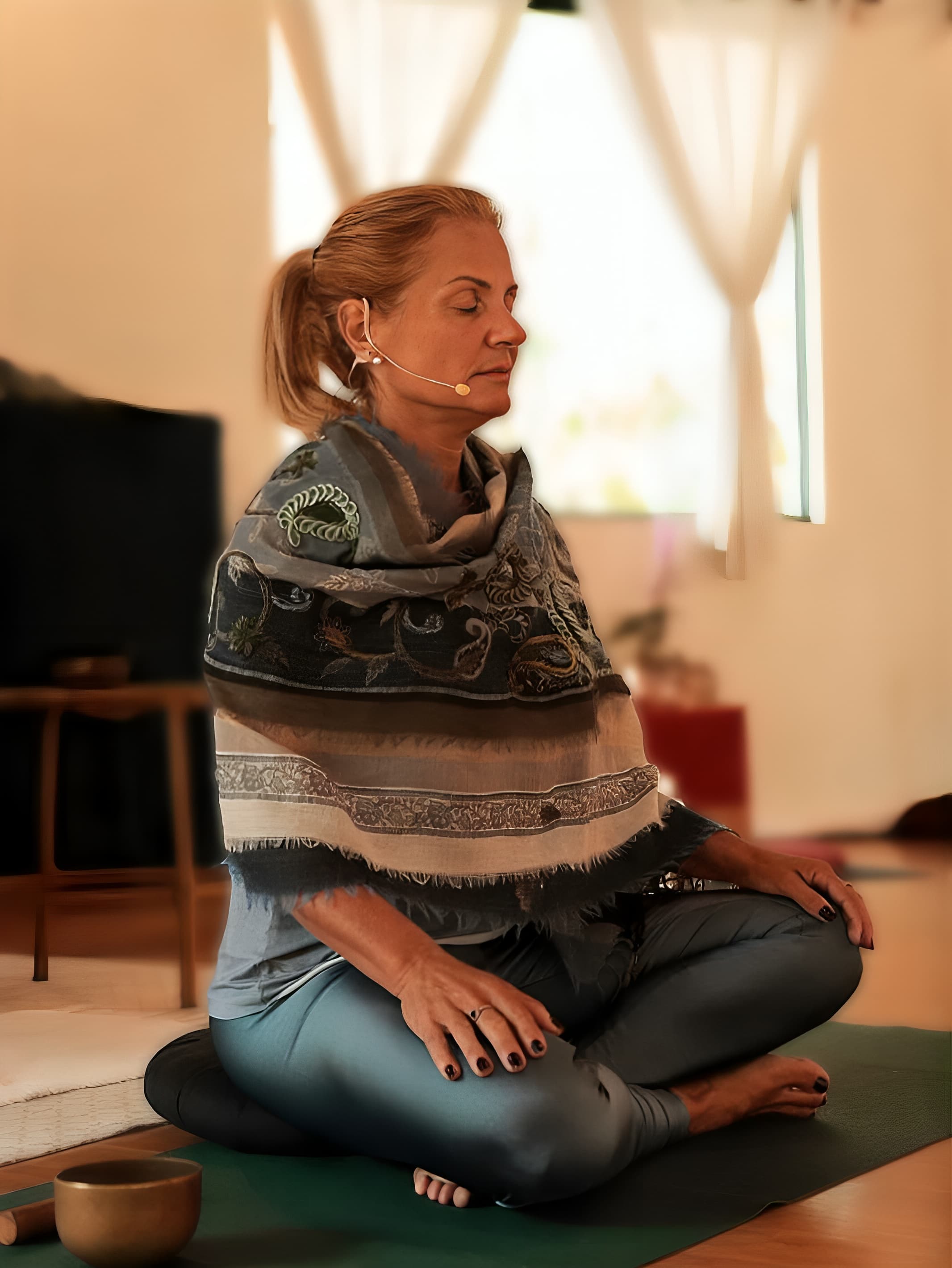 Deni Miranda em postura de meditação, com xale indiano, luz natural